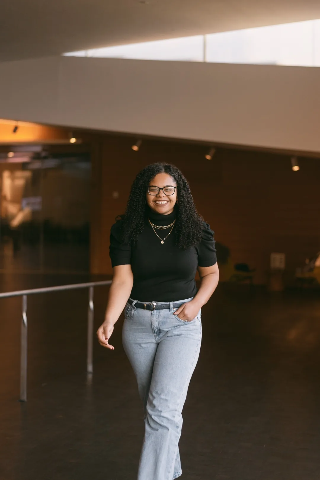 Nicole Olaniyi walking through a university hall, smiling.