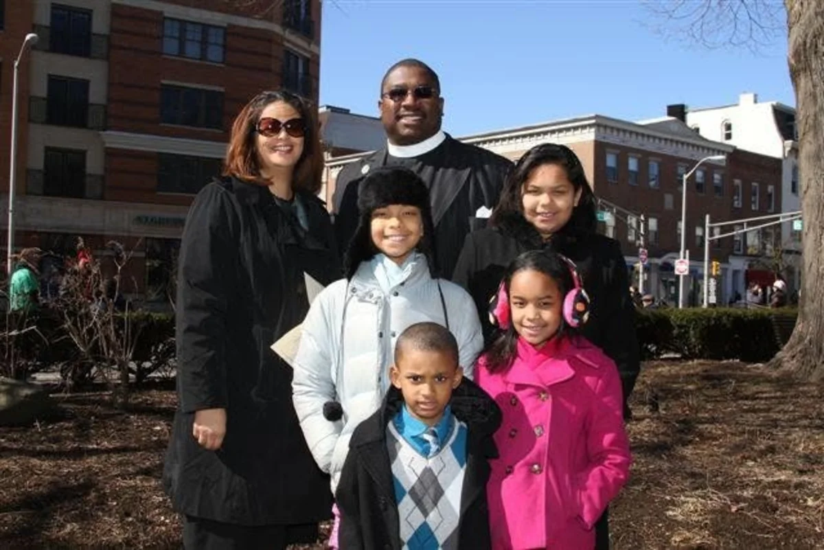 The Olaniyi family — both parents with their four children — photographed together outdoors.